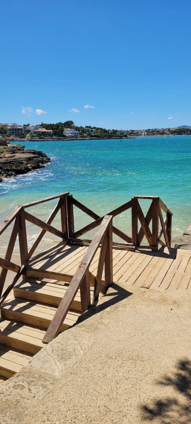 Holztreppe hinunter zur Bucht mit türkisblauem Wasser