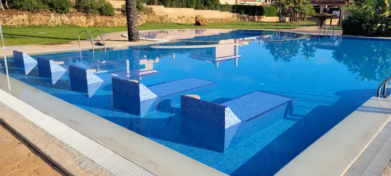 Pool mit gemauerten Unterwasser-Liegen aus blauem Mosaik
