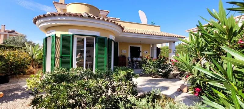 Gartenansicht der Villa mit grünen Fensterläden und bepflanztem Vorgarten