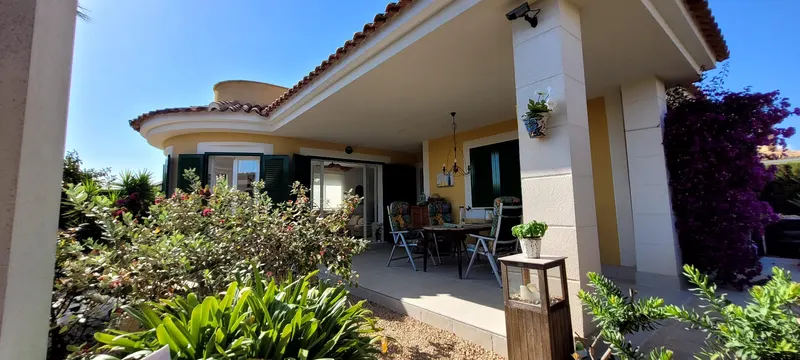 Überdachte Terrasse der Villa mit Esstisch und violetter Bougainvillea