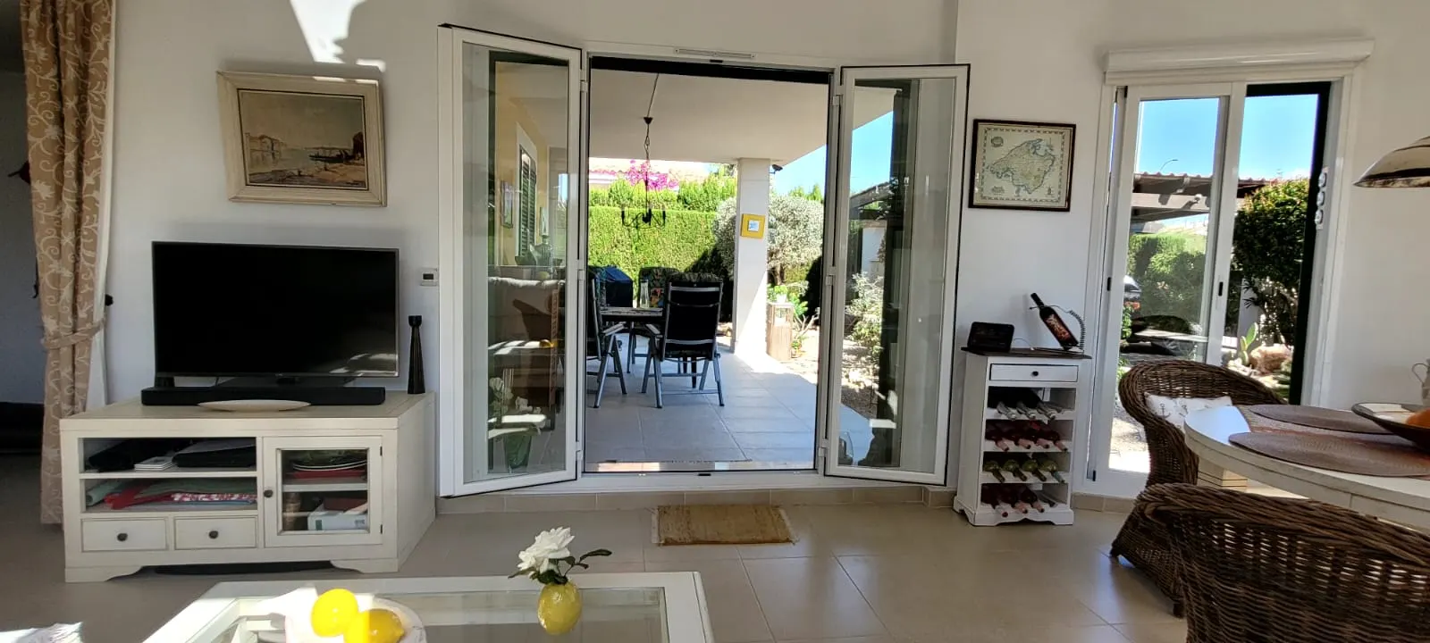Helles Wohnzimmer mit weit geöffneten Falttüren zur überdachten Terrasse