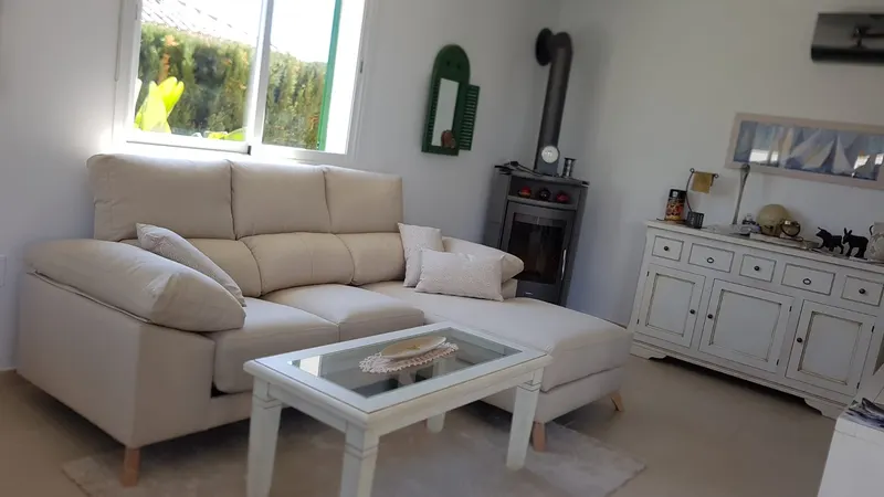 Wohnzimmer mit heller Eckcouch, Couchtisch und Kaminofen